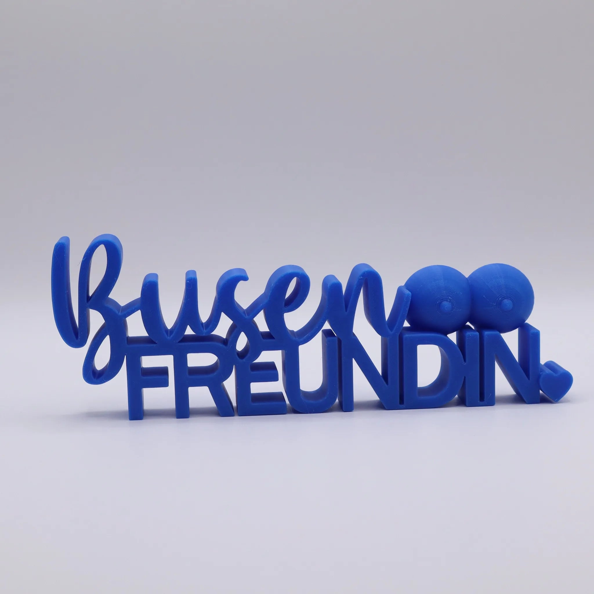 3D-gedrucktes Deko-Statement in Blau mit dem Schriftzug Busenfreundin, verziert mit Busen-Symbolen und Herz