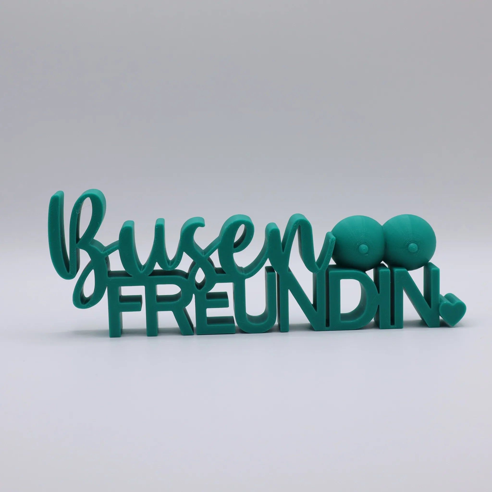 3D-gedrucktes Deko-Statement in Grün mit dem Schriftzug Busenfreundin, verziert mit Busen-Symbolen und Herz