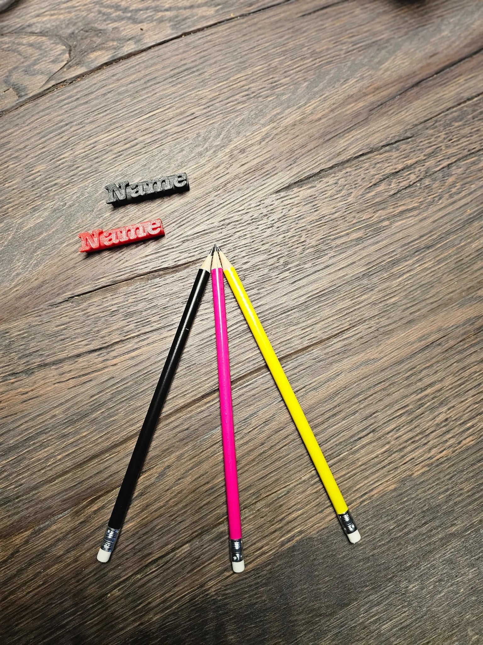 Drei Bleistifte in Pink, Schwarz und Gelb mit gravierten Namensclips – perfekte Kombination zum KlassenStar Namenshalter für die Schule.