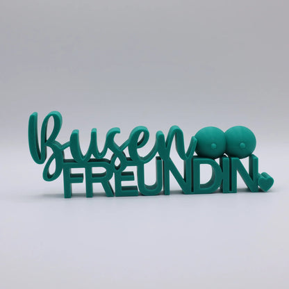 3D-gedrucktes Deko-Statement in Grün mit dem Schriftzug Busenfreundin, verziert mit Busen-Symbolen und Herz