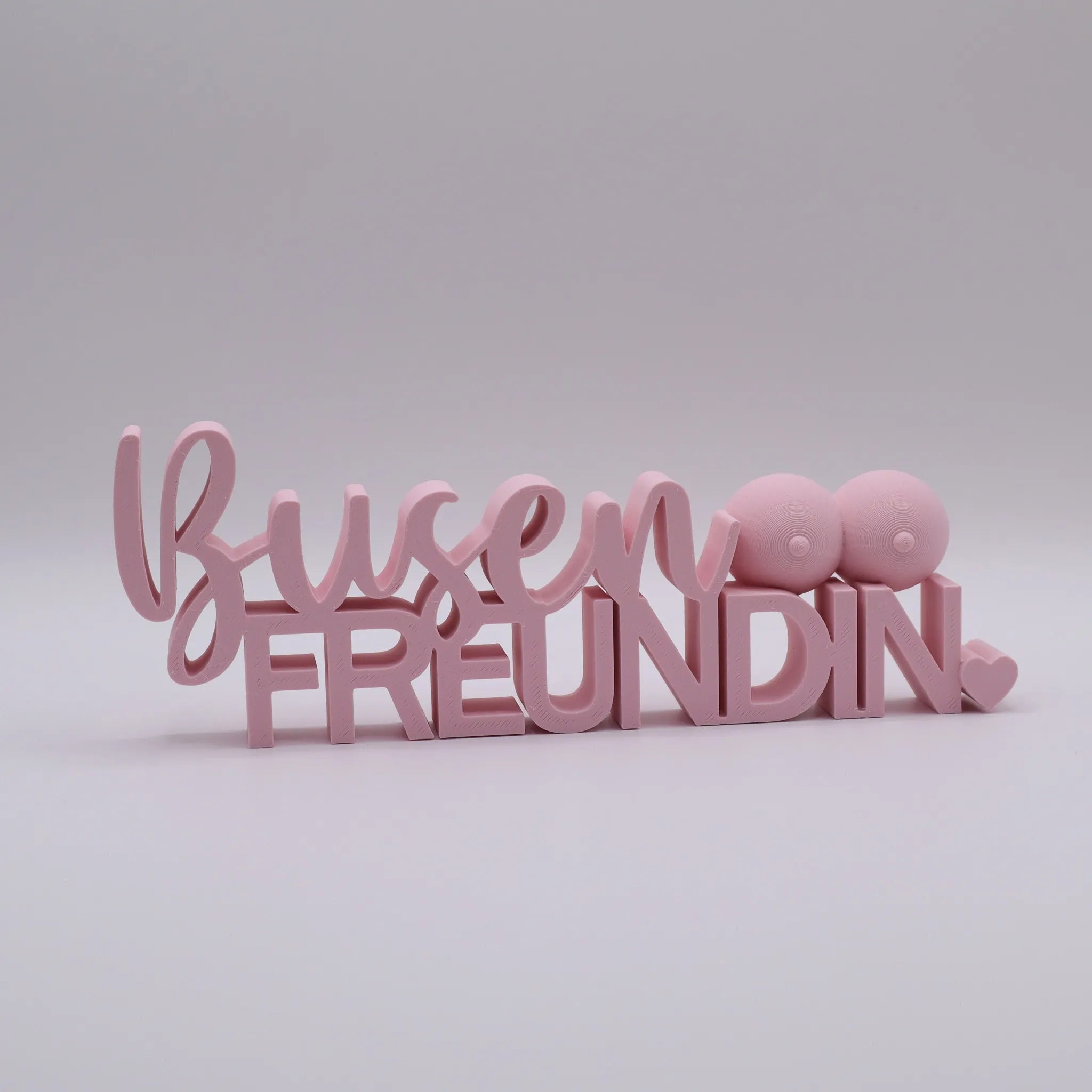 3D-gedrucktes Deko-Statement in Rosa mit dem Schriftzug Busenfreundin, verziert mit Busen-Symbolen und Herz