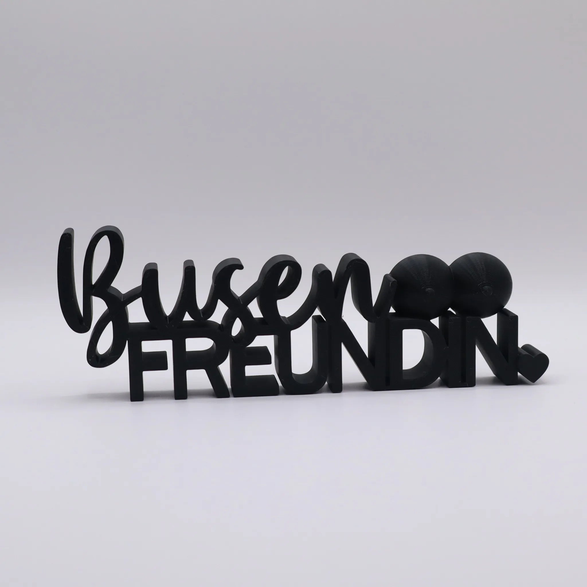3D-gedrucktes Deko-Statement in Schwarz mit dem Schriftzug Busenfreundin, verziert mit Busen-Symbolen und Herz