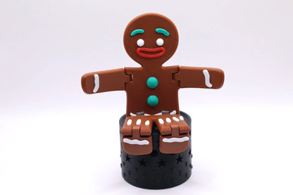 Mudivo GingerMood – bewegliche Lebkuchenfigur sitzend auf schwarzem Podest. Fröhliche Weihnachtsdeko mit Stil und Herz. 🎄✨