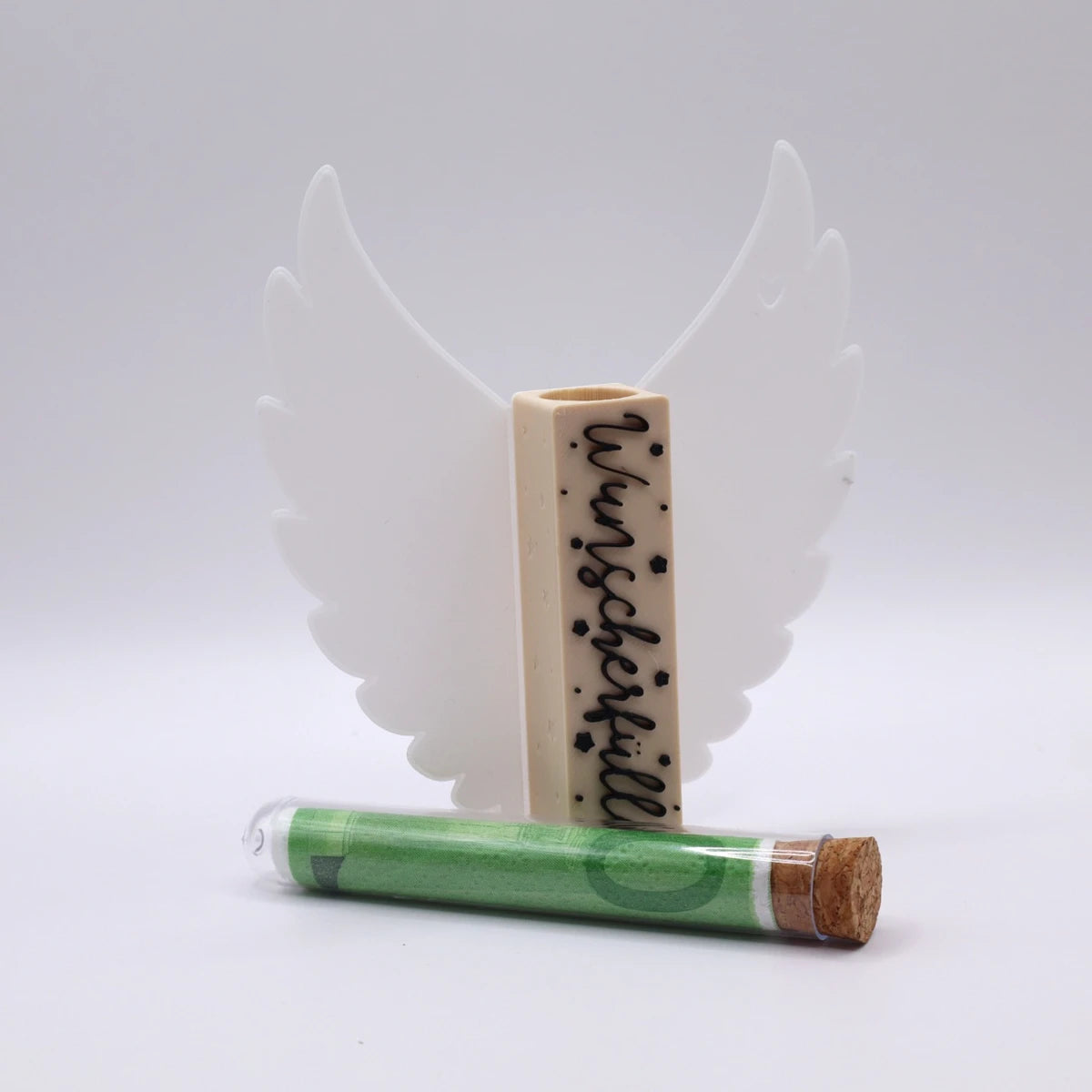 Mudivo WishYouXmas – Aufsteller mit weißen Flügeln, schwarzer Schrift und beigem Körper. Reagenzglas liegt davor – stilvolles Geldgeschenk zu Weihnachten. 🎄