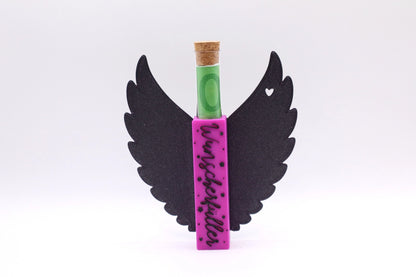 Mudivo Wunscherfüller – Aufsteller mit schwarzen Flügeln, pinkem Körper und eleganter Schrift. Reagenzglas eingesteckt – edles Geschenk mit Charakter und Herz. 💝